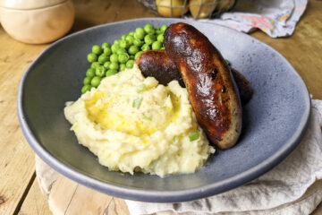 Cheese and onion mashed potatoes with a drizzle of olive oil on top, gluten free Lidl sausages and peas. Served in a cute blue bowl from Flying Tiger.