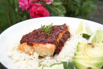 Grilled salmon with raspberry sauce and fresh thyme on top, served on rice